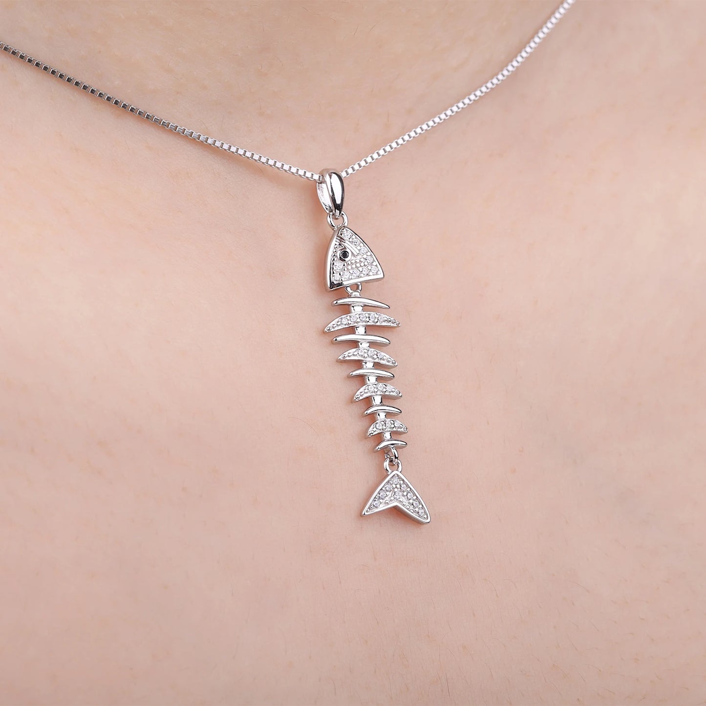 Sterling silver fishbone pendant with black spinel stones shown on a model’s neck for size reference