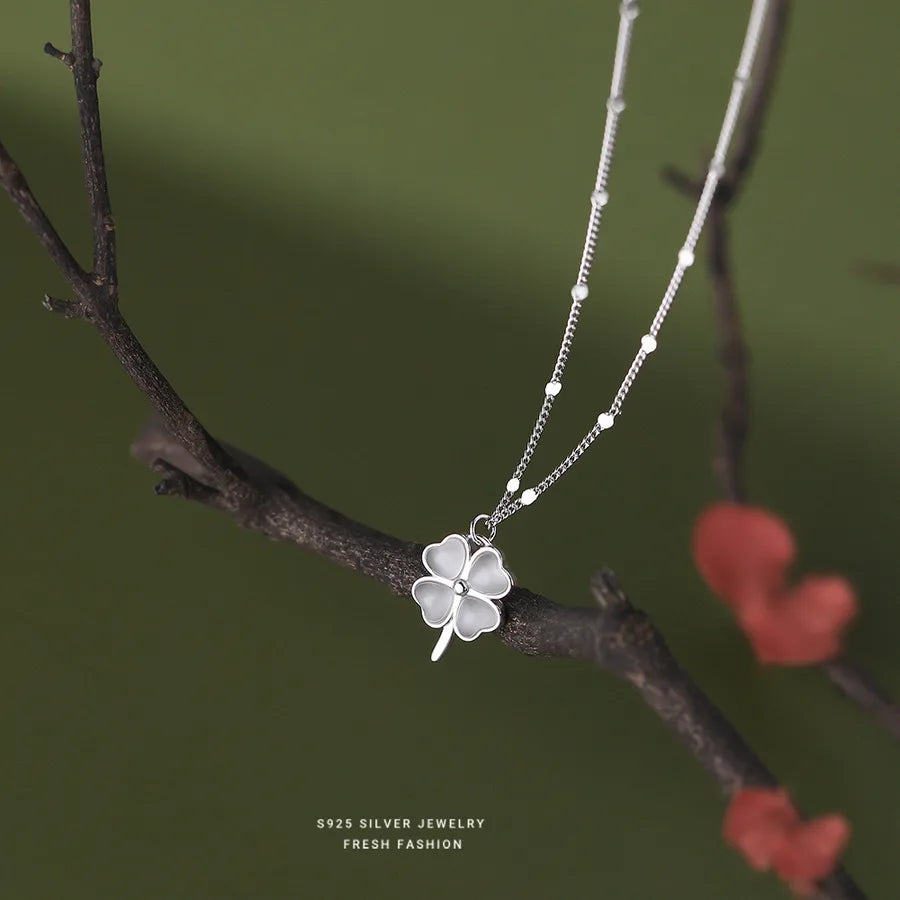 Four-leaf clover pendant necklace with cat’s eye stone hanging on branch