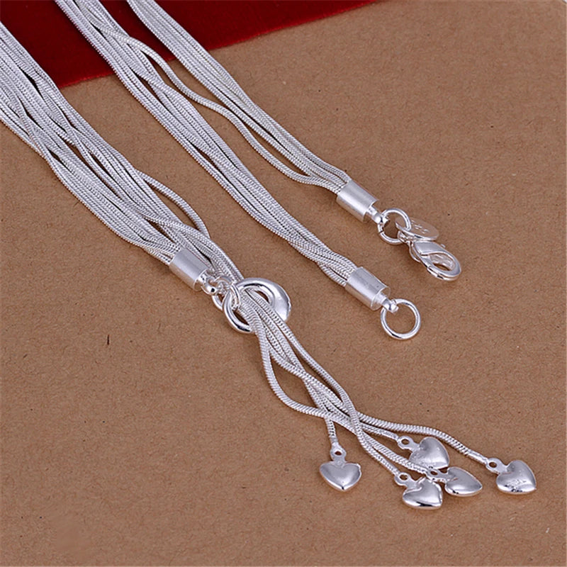 Close-up of silver multi-strand necklace clasp and dangling crystal teardrops on brown background