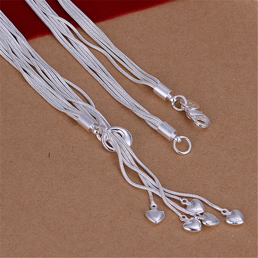 Close-up of silver multi-strand necklace clasp and dangling crystal teardrops on brown background