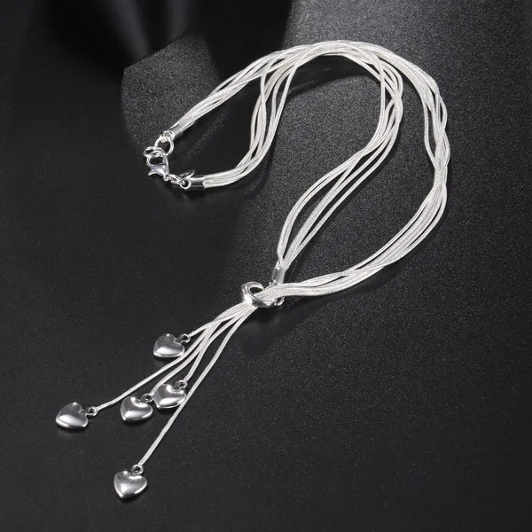 Multi-strand sterling silver necklace with teardrop crystal charms displayed on black fabric