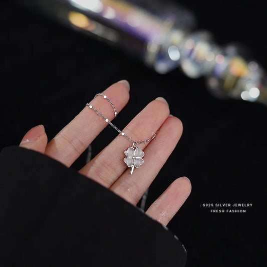 Close-up of silver four-leaf clover necklace and matching ring