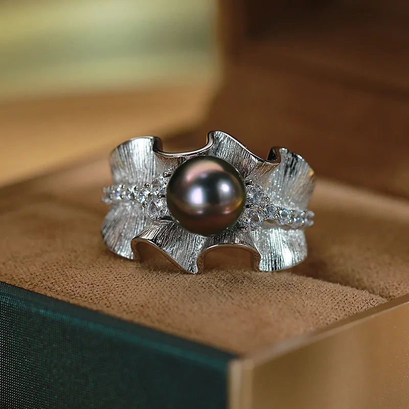 Front view of luxury silver-tone wave ring with black pearl and crystal accents in jewelry box
