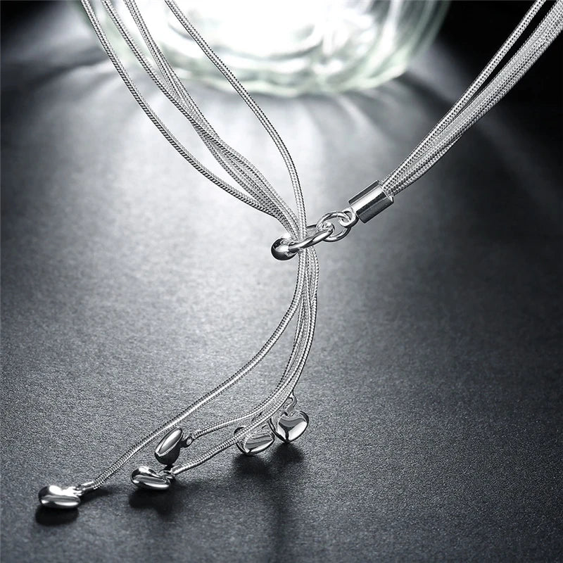Silver layered necklace with crystal teardrops displayed on metallic silver surface