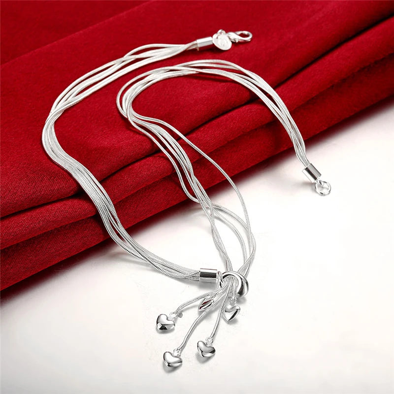 Two elegant silver multi-strand necklaces with crystal drops arranged on red fabric