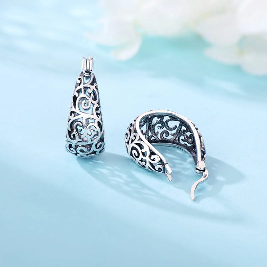 Vintage vine design silver hoop earrings displayed on a light blue background