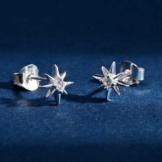 Close-up of 925 sterling silver North Star stud earrings with zircon on dark blue background