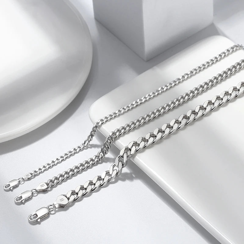 Close-up of 925 sterling silver Cuban link and Figaro link bracelets with lobster clasps, rhodium plated for high shine and tarnish resistance.