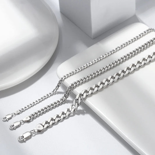 Close-up of 925 sterling silver Cuban link and Figaro link bracelets with lobster clasps, rhodium plated for high shine and tarnish resistance.