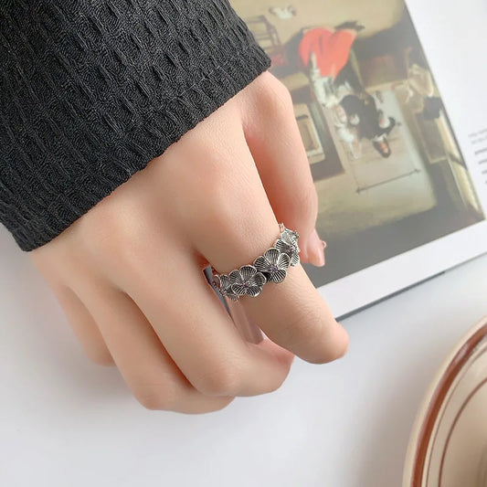 Woman wearing a vintage-style 925 sterling silver floral ring with purple zircon stones, shown on hand for size reference