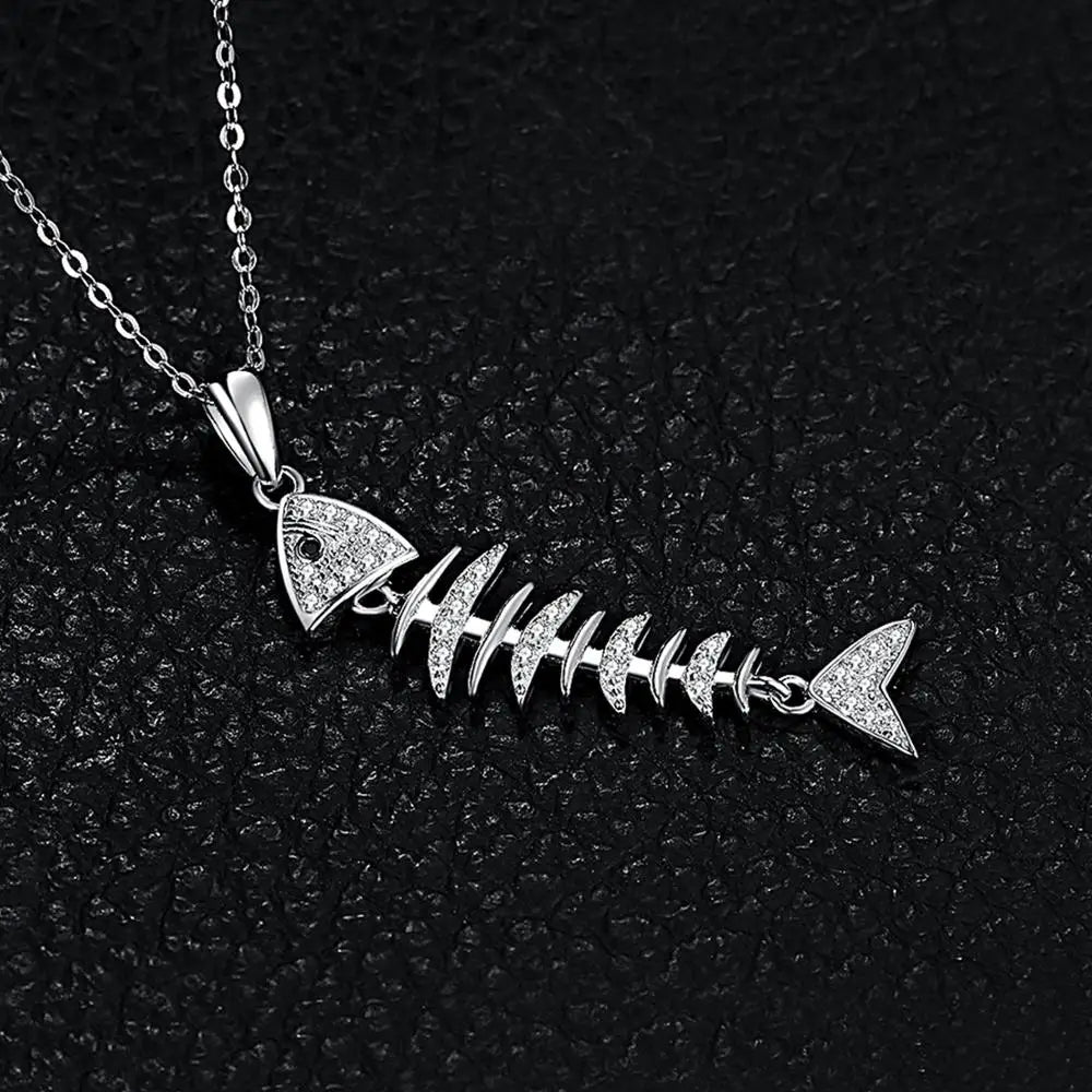 Close-up of sterling silver fishbone pendant with sparkling black spinel stones on a black textured surface